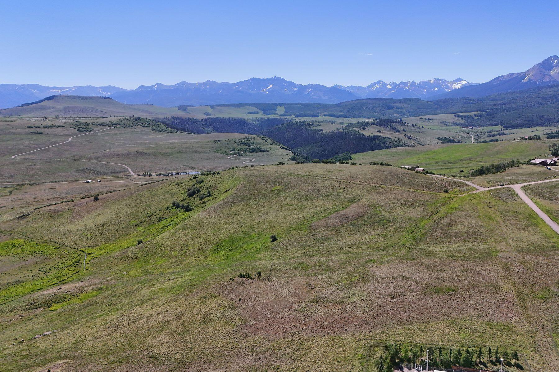 Aerial view of rolling open land with winding roads and distant mountain views.