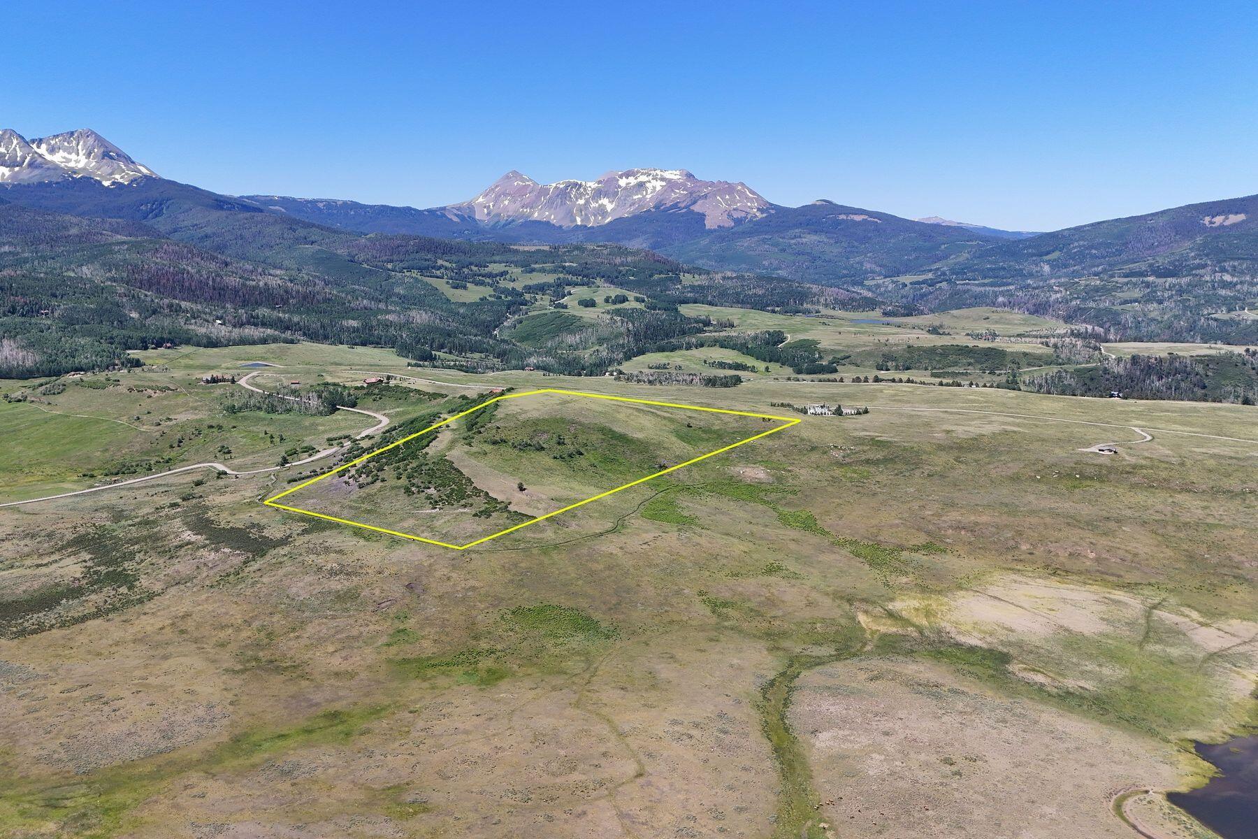 Aerial view of a yellow-outlined grassland parcel with snow-dusted mountains in the distance.