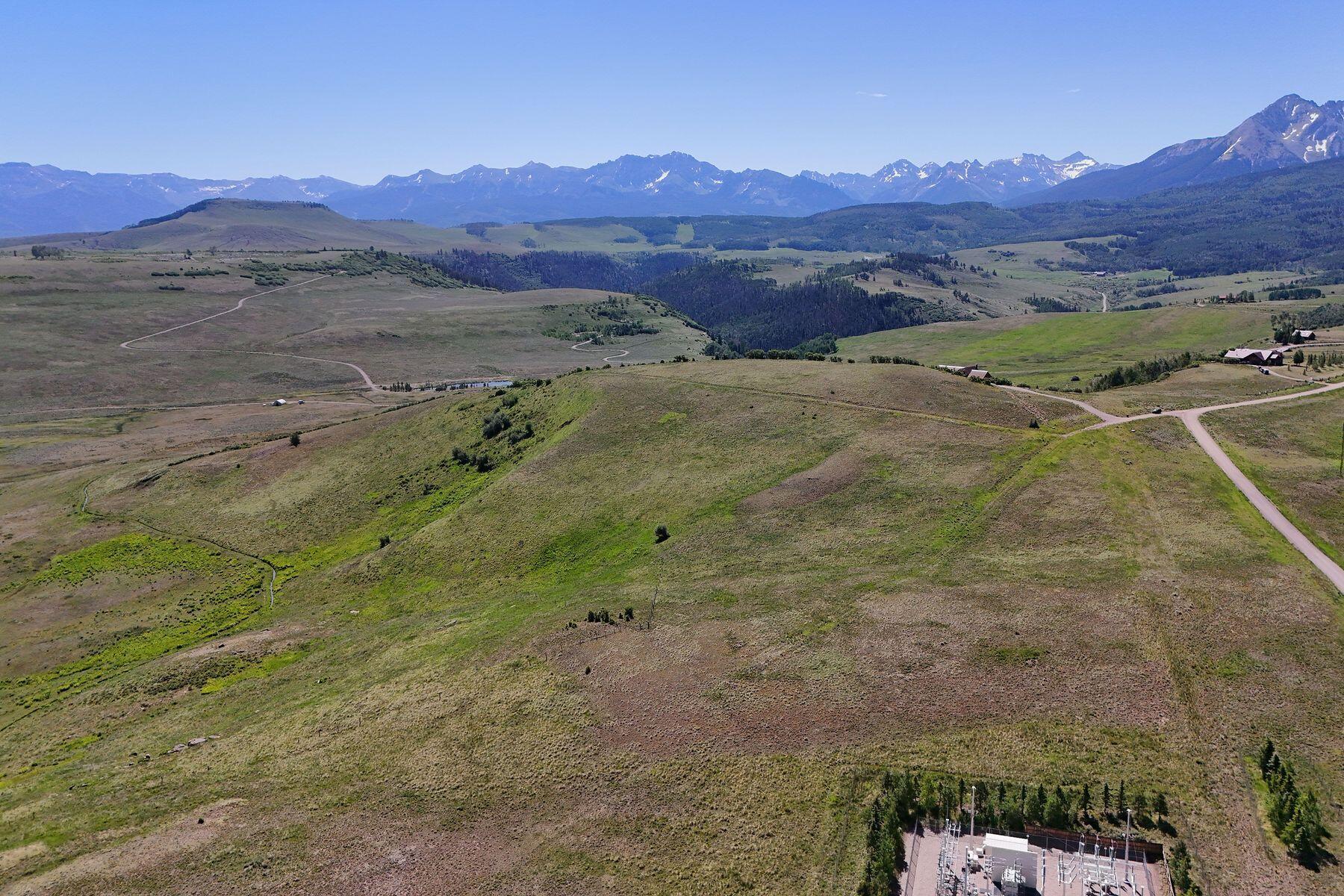Open rolling acreage and winding roads with a broad mountain range in the distance.