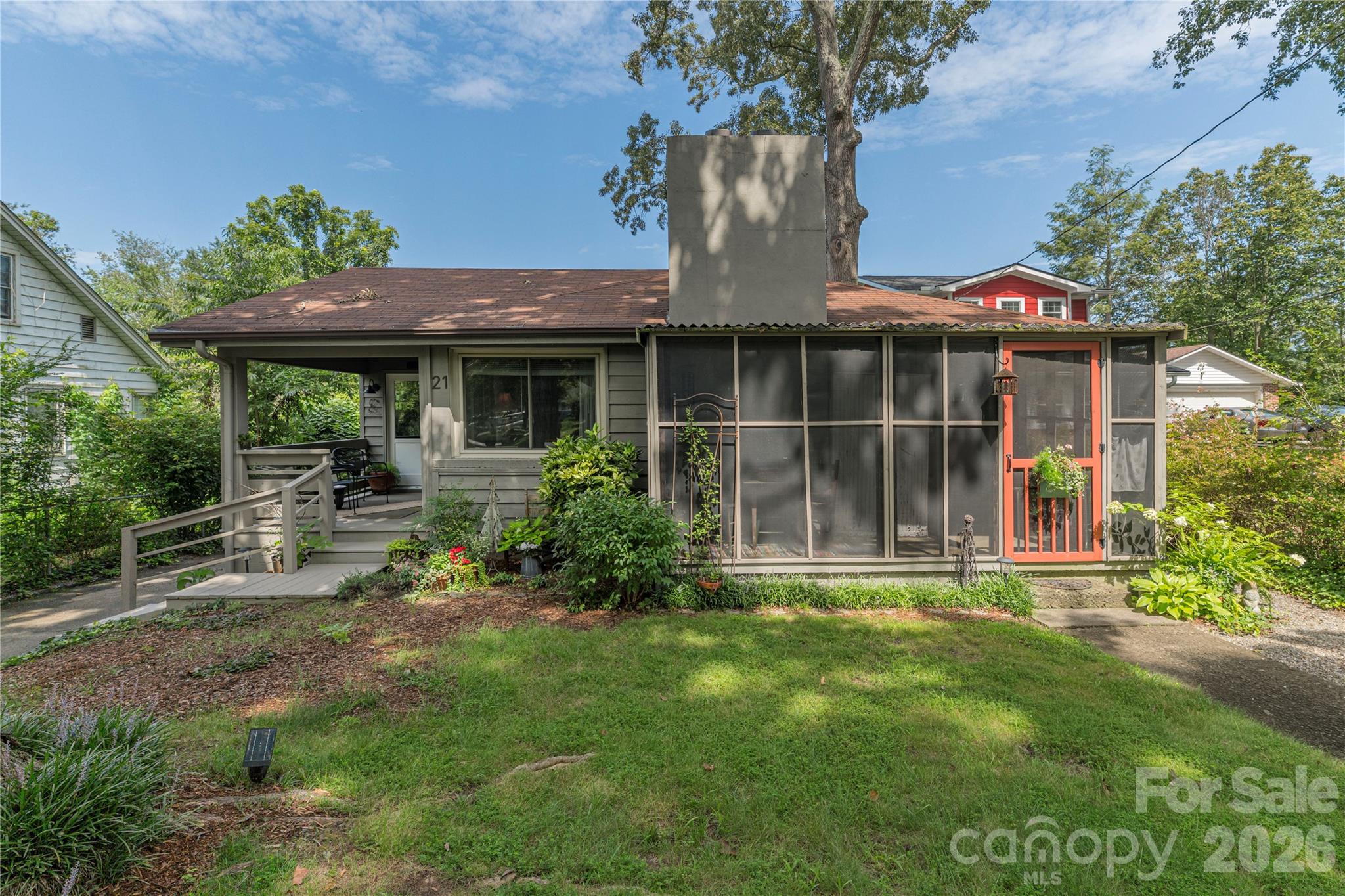 House at 21 Lincoln Avenue with a screened porch, coral-red door, and ramped front entry.