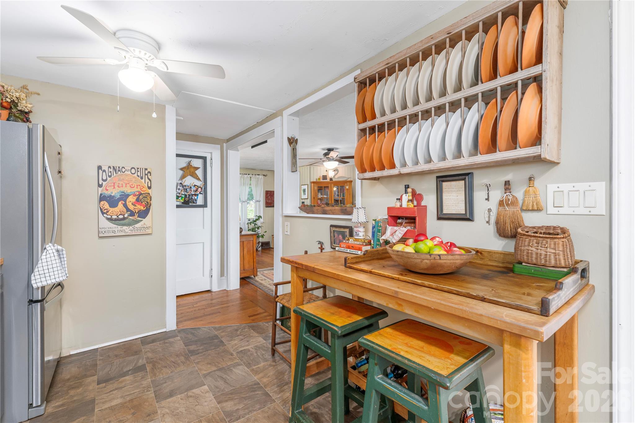 Kitchen with a wooden worktable and a wall-mounted rack of orange and white plates.