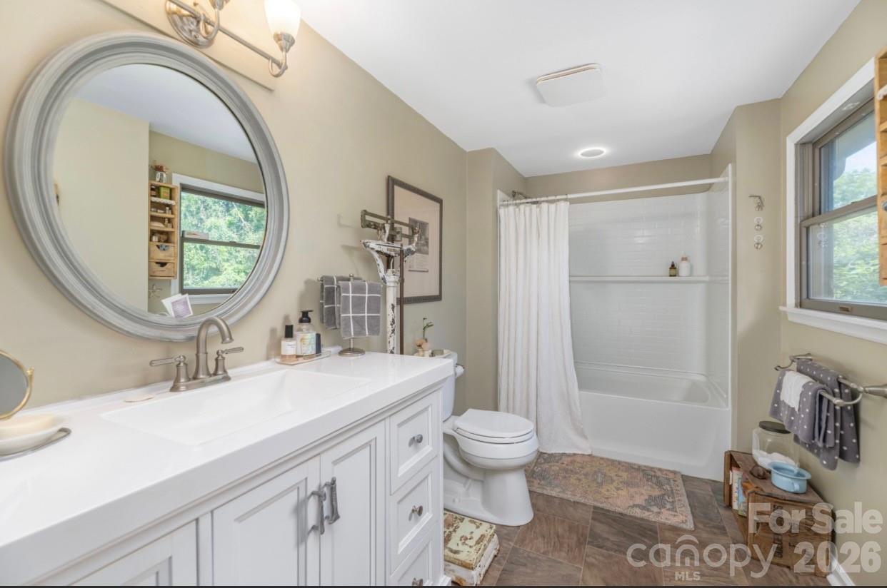 Bathroom with a white vanity, round mirror, and tub-shower with a white curtain.