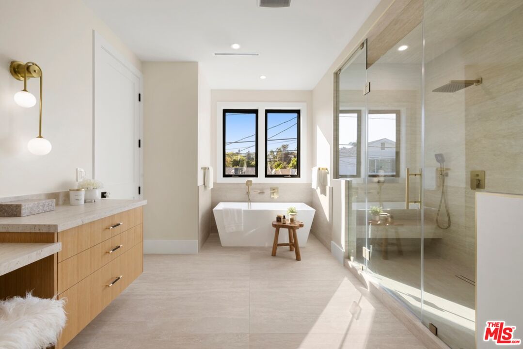Bright bathroom with a freestanding tub, glass-enclosed shower, and light wood vanity.