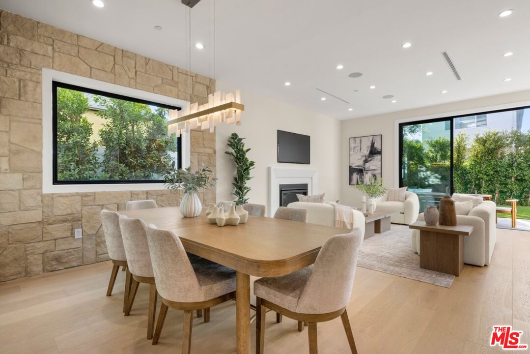 Open-plan dining and living room with a stone wall, fireplace, and garden views.