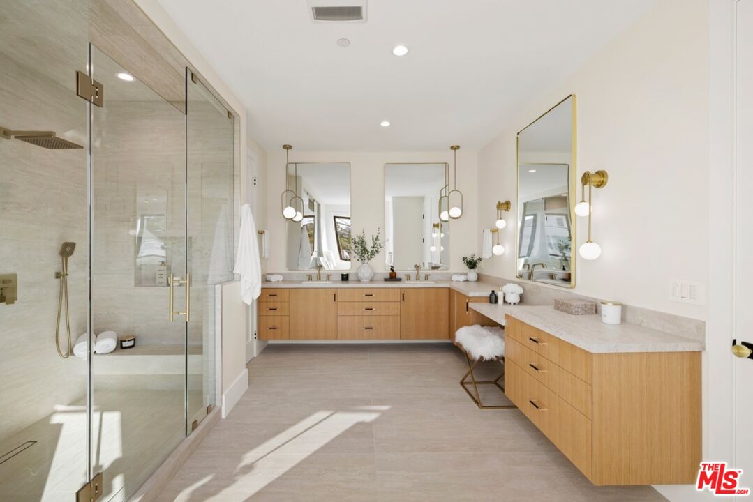 Modern bathroom with a glass walk-in shower and long double vanity with light wood cabinets.