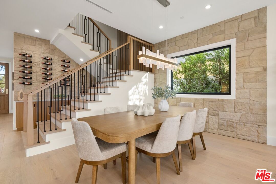 Dining room with a wood table, stone walls, staircase, and built-in wine racks.