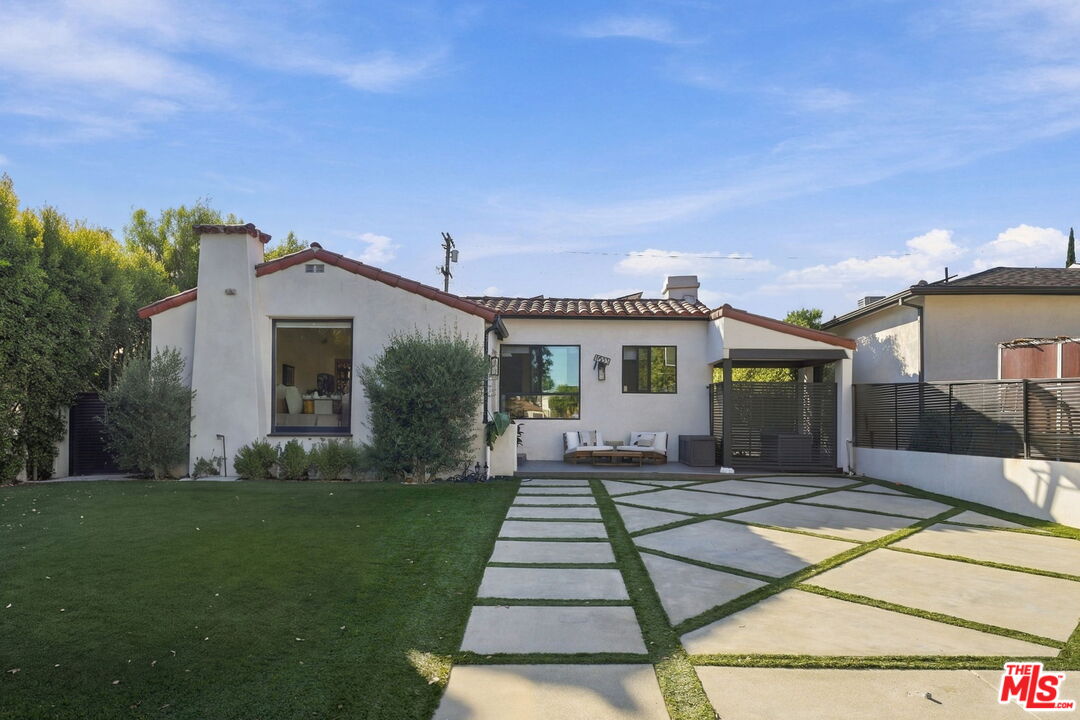 Single-story white stucco home with a tile roof, front lawn, and covered patio.