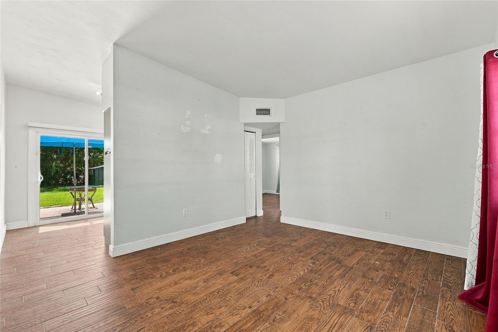 Empty room with wood-look flooring, a sliding glass door, and a view of the patio.