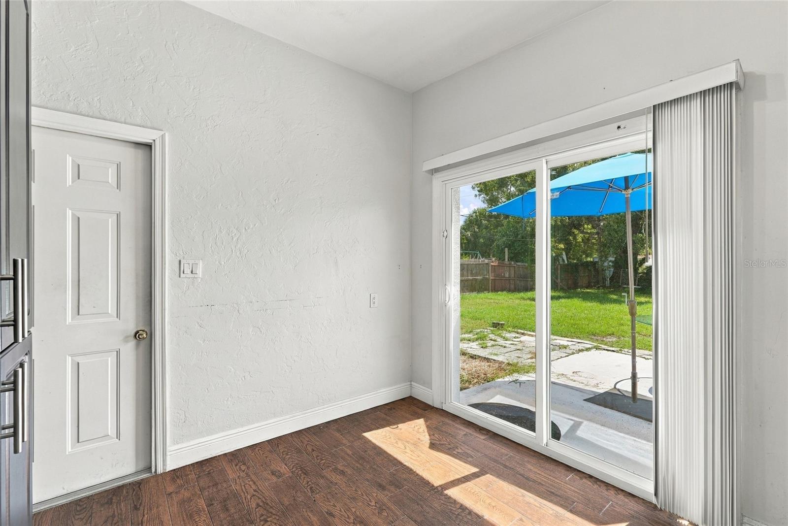 Vacant room with wood-look flooring and sliding glass doors overlooking a fenced backyard.