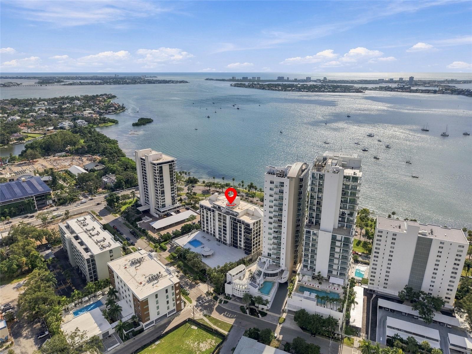 Aerial view of waterfront Sarasota high-rises and Sarasota Bay, with a red pin marking a building.