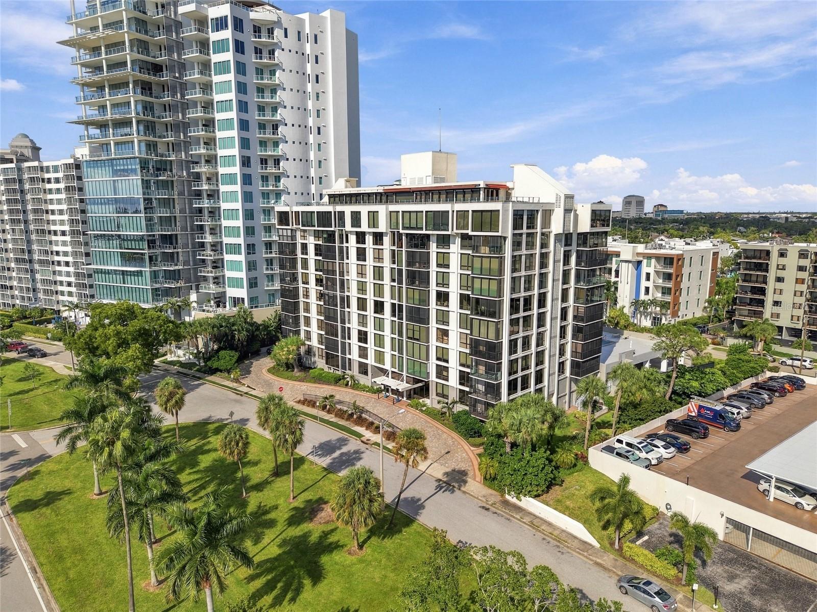 Modern condominium buildings with glass balconies, palm trees, and landscaped grounds in downtown Sarasota.
