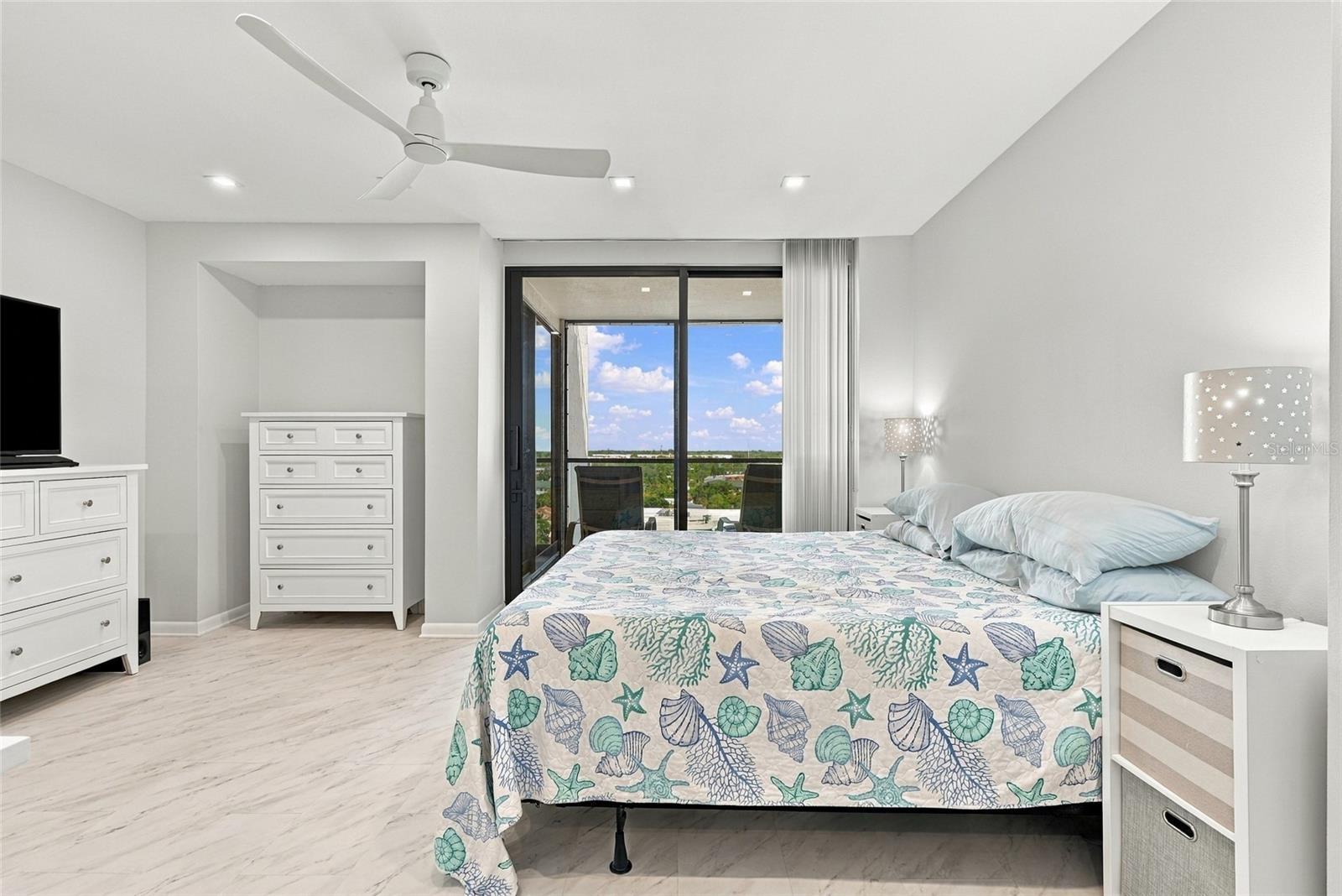 Bedroom with a sea-life-patterned bedspread and sliding doors to a balcony.
