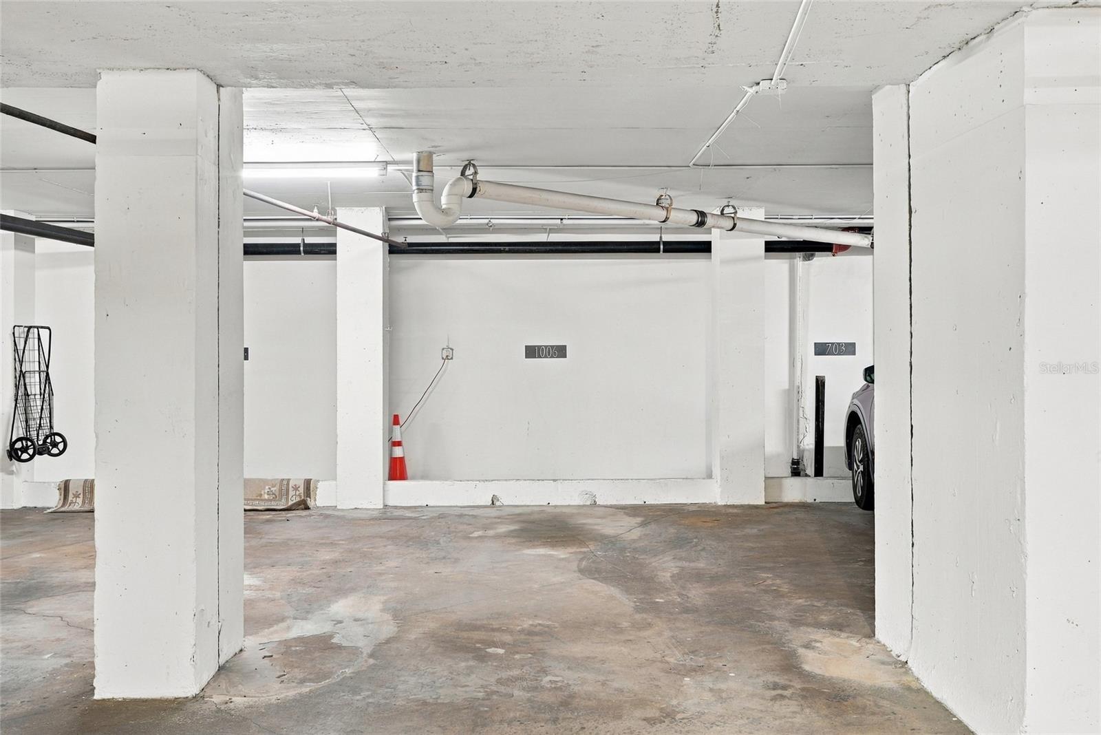 Parking space 1006 in a concrete garage, framed by white columns with exposed overhead pipes.