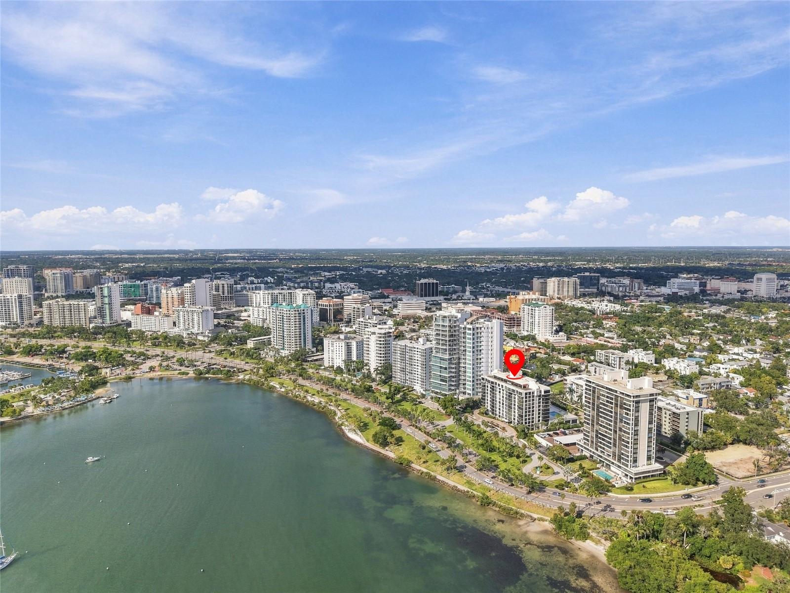 Aerial view of downtown Sarasota and the bay, with a red pin marking a condominium building.