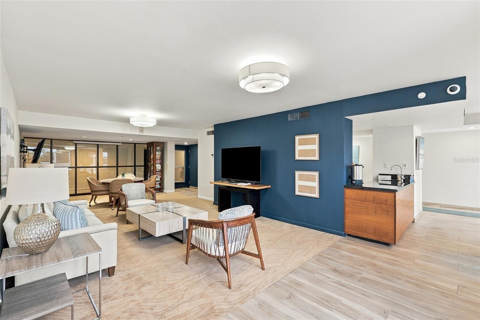 Open-plan condo living room with a blue accent wall, dining area, and wood-front counter.