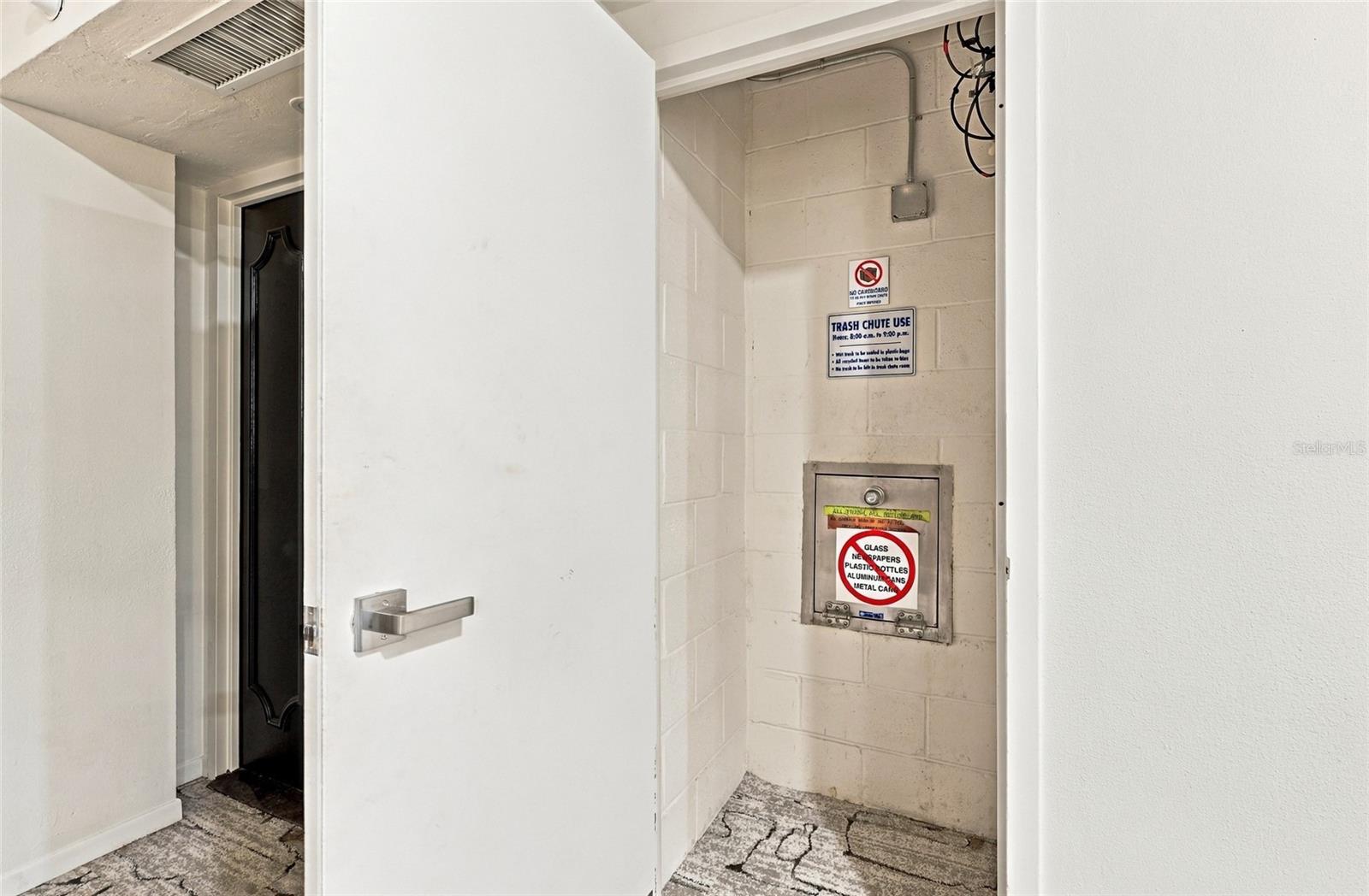 Condominium trash chute area with an open door and posted disposal instructions.