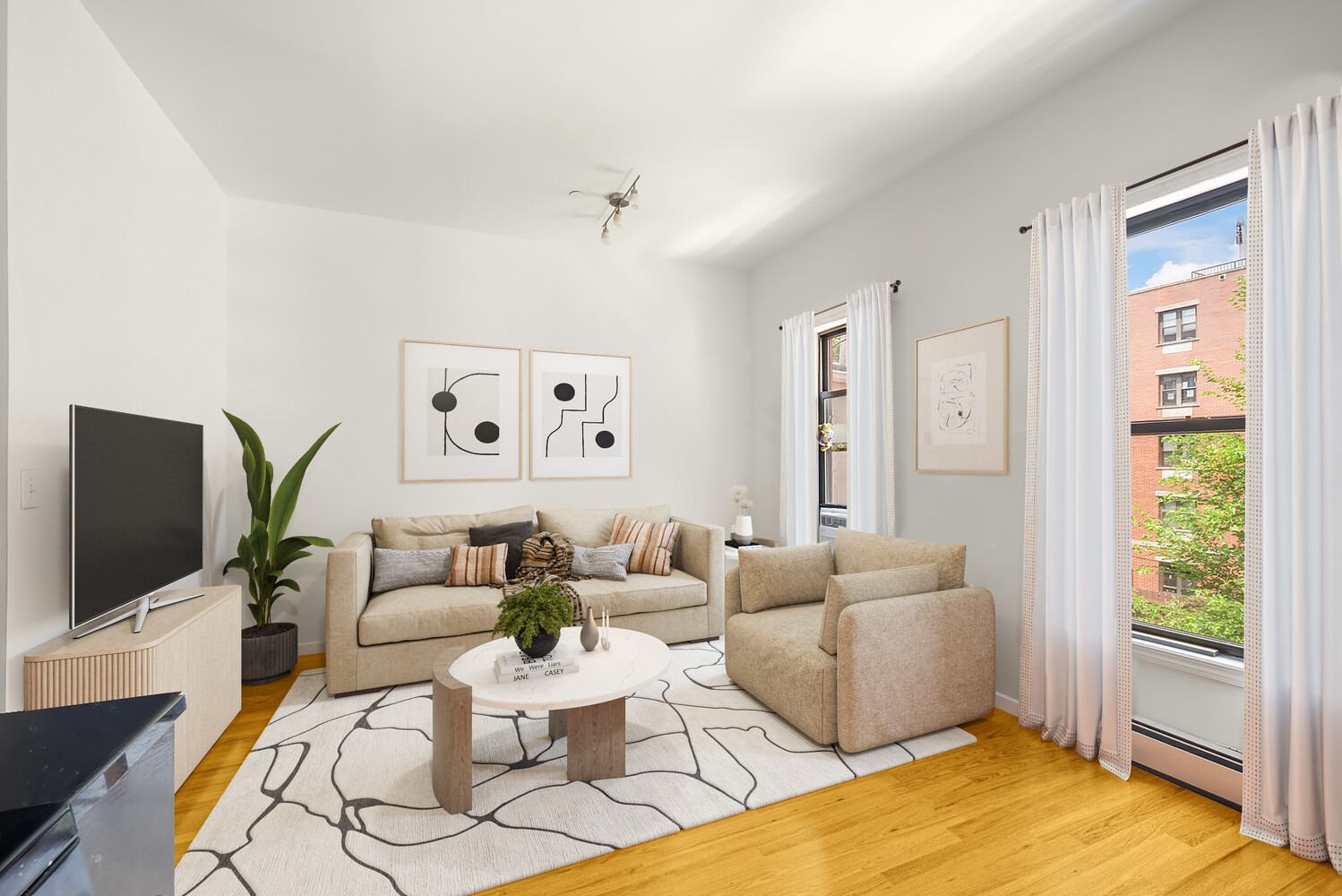 Furnished living room with beige seating, a patterned rug, and tall windows overlooking a brick building.