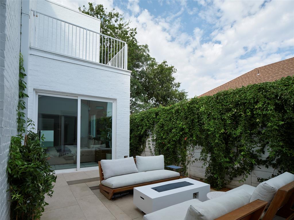Courtyard patio with white brick exterior, sliding glass doors, and lounge seating.