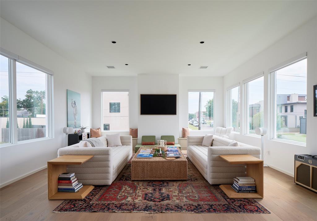Bright living room with facing white sofas, a patterned rug, and large windows.