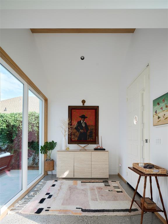 Bright living area with a wood console, framed artwork, patterned rug, and glass doors to the patio.