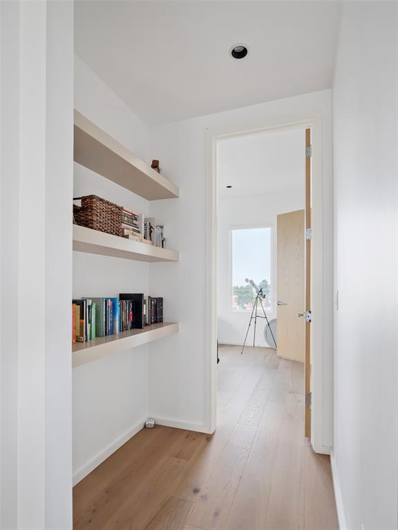 Bright hallway with built-in book shelves and an open doorway to a sunlit room.