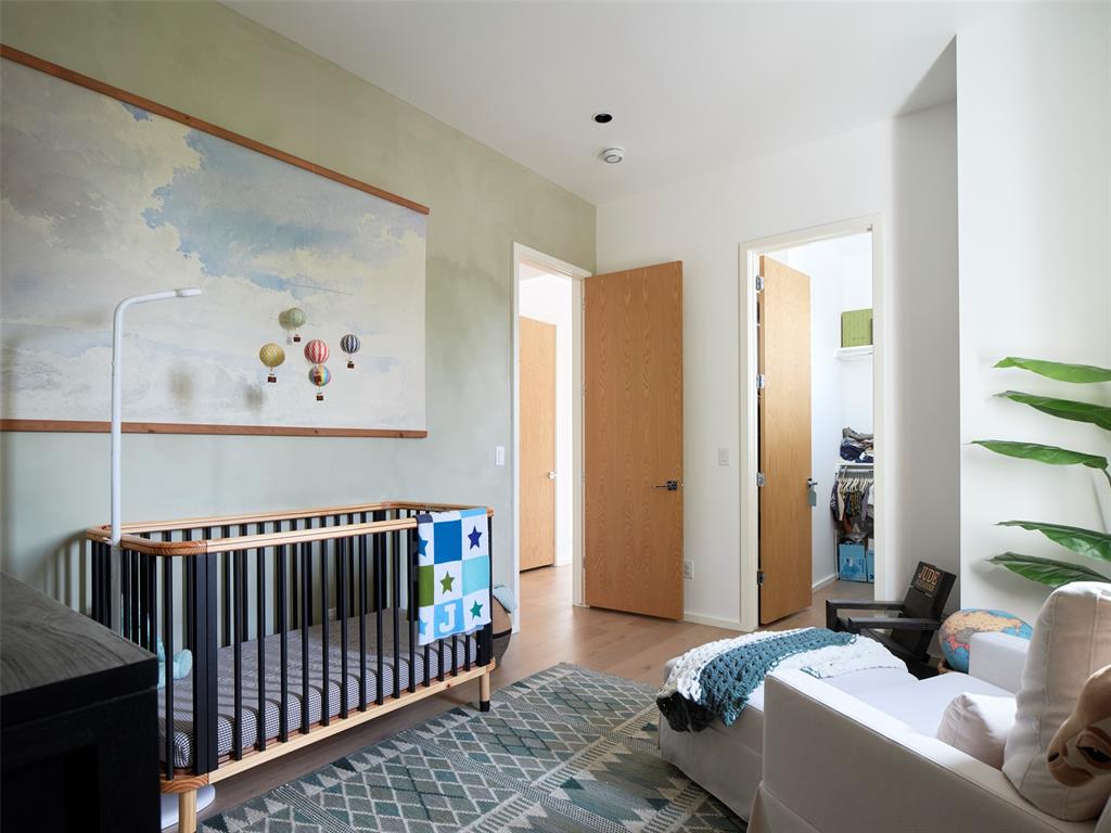 Nursery with a wooden crib beneath a cloud mural and a white sofa.