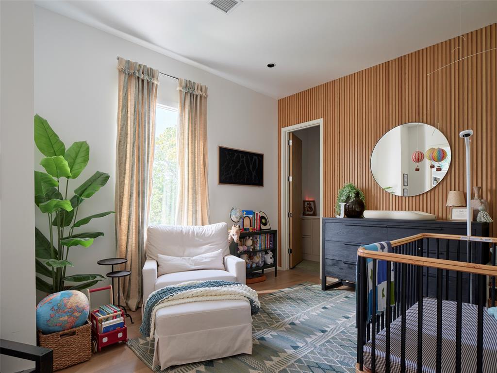 Nursery with a black crib, white chair, and wood-slat accent wall.
