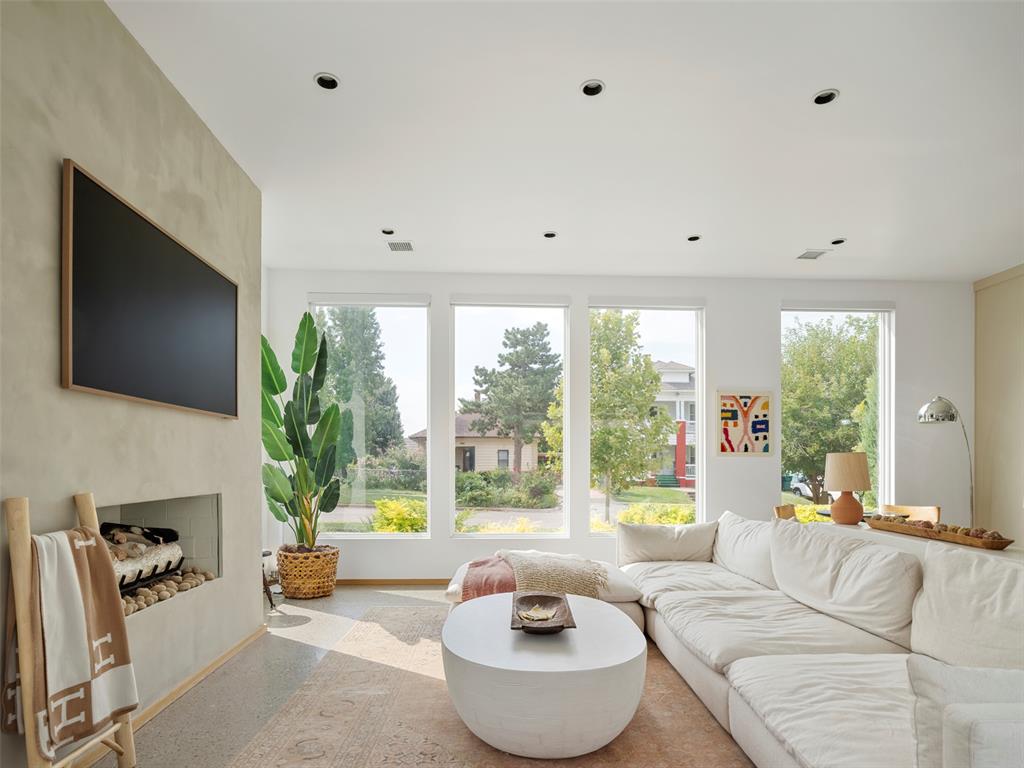 Living room with a white sectional, round coffee table, fireplace, and tall street-facing windows.