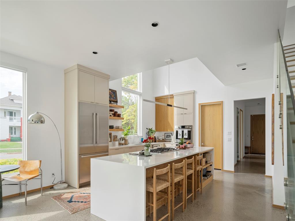 Modern kitchen with a long island, woven-seat bar stools, and tall windows.