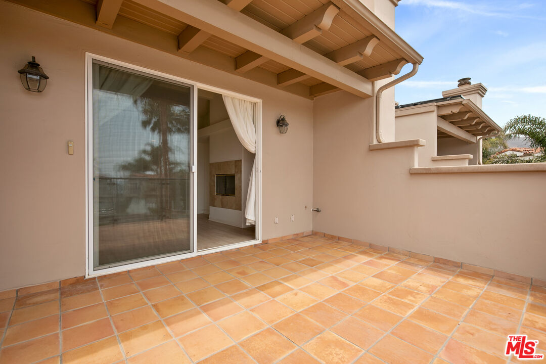 Covered patio with terracotta tiles and an open sliding glass door.