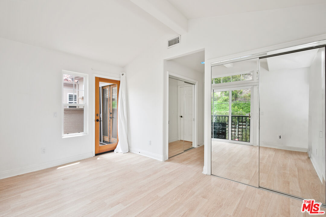 Bright empty room with mirrored closet doors and a glass door to a balcony.