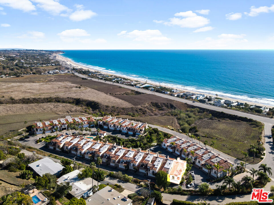Aerial view of coastal homes near the Malibu shoreline, with the Pacific Ocean beyond.