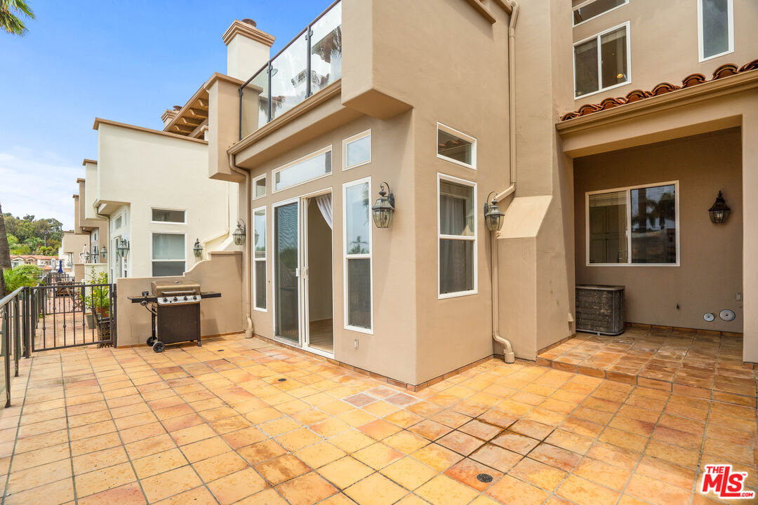 Tiled courtyard patio with sliding glass doors and a barbecue grill.