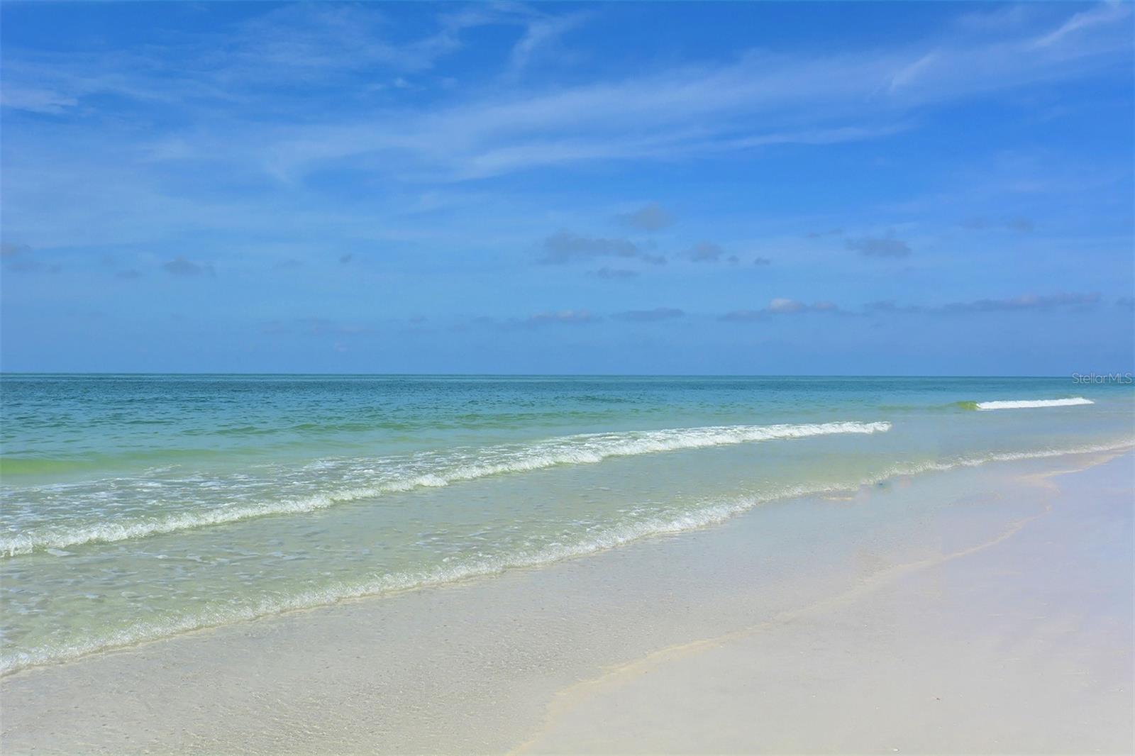 Sandy beach and turquoise shoreline beneath a broad blue sky.