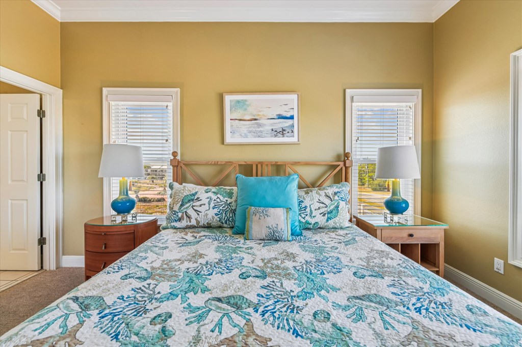 Bedroom with teal floral bedding, blue accent pillows, and mustard-yellow walls.