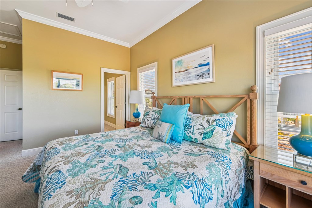 Bedroom with a teal floral bedspread, wooden cross-braced headboard, and mustard-yellow walls.