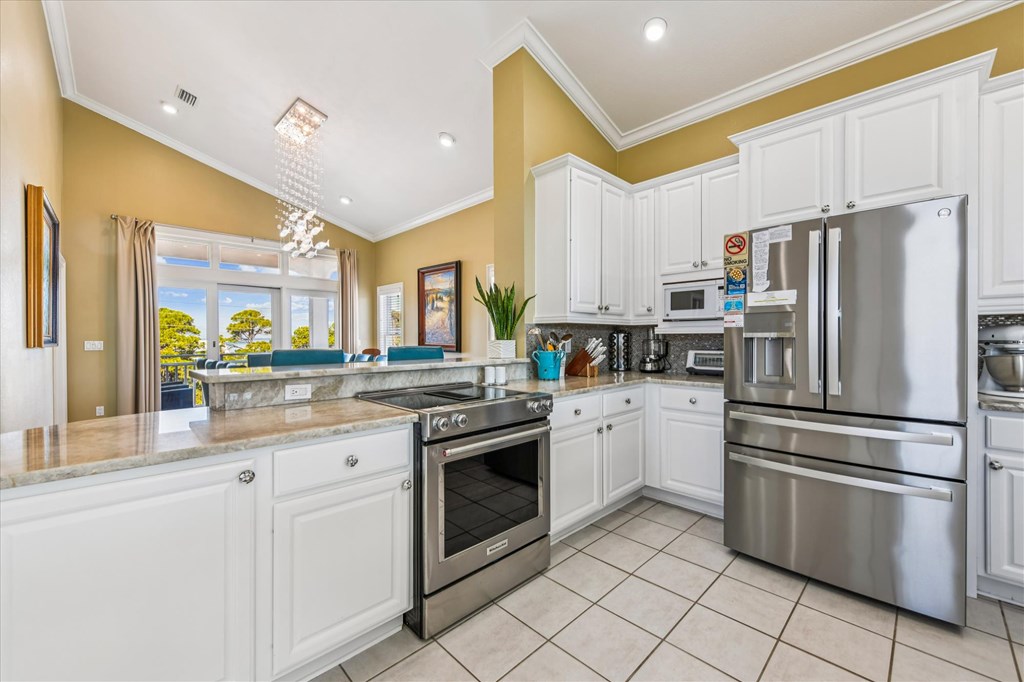 Kitchen with white cabinetry, stainless steel appliances, and a breakfast bar overlooking a dining area.