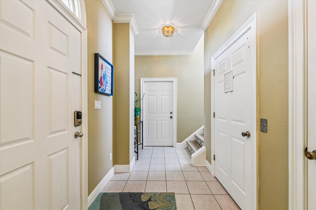 Tiled entry hallway with white paneled doors, a small staircase, and a potted plant.