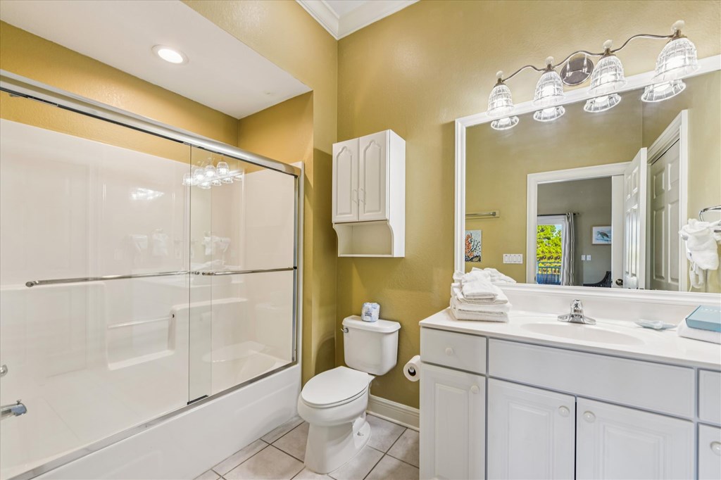 Bathroom with a glass-enclosed tub and shower, white vanity, large mirror, and folded towels.