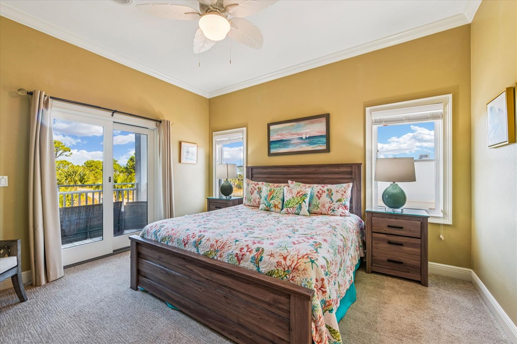 Bedroom with a floral bedspread, dark wood furniture, and sliding doors to a balcony.