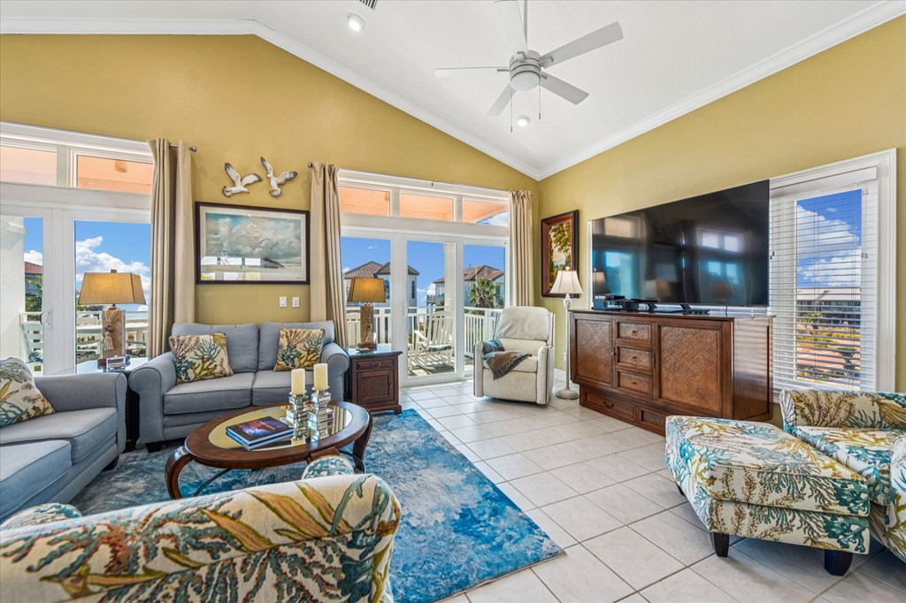 Living room with vaulted ceiling, blue seating, and glass doors overlooking the water.