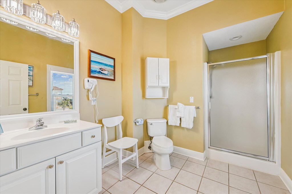 Bathroom with a white vanity, tiled shower, and yellow walls.
