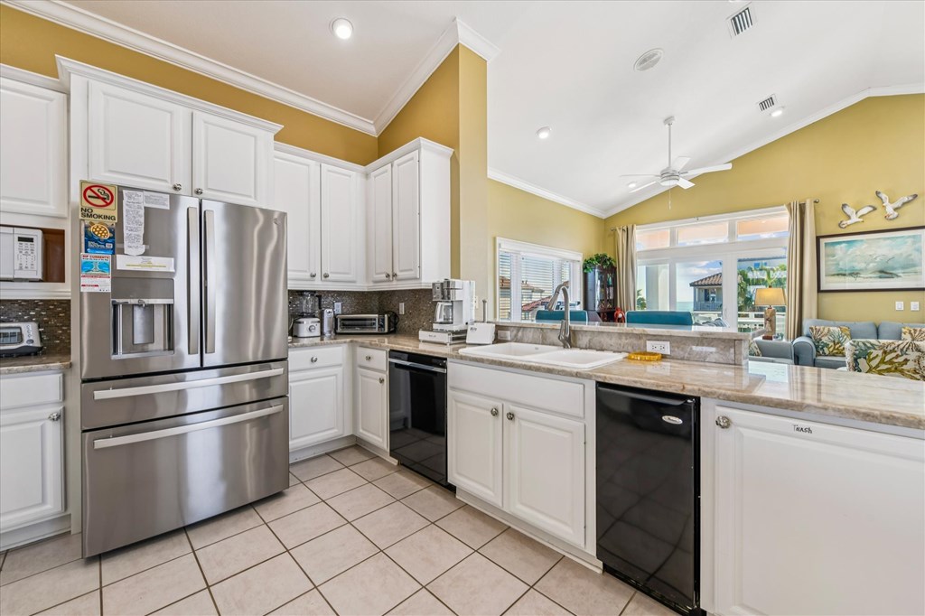Kitchen with white cabinets, stainless appliances, and a granite breakfast bar opening to the living area.