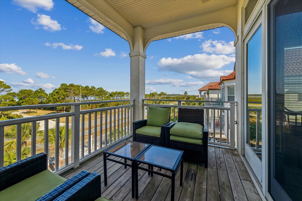 Covered balcony with wicker seating and coastal marshland visible beyond the railing.