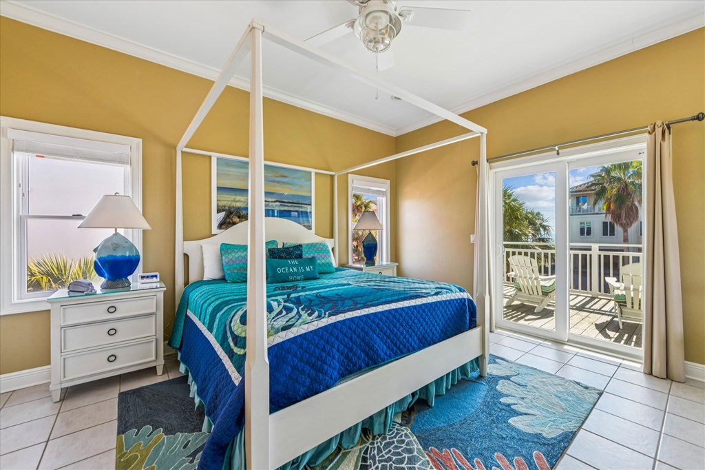 Bedroom with a white four-poster bed, turquoise bedding, and sliding doors to a balcony.