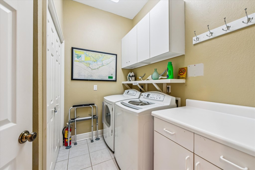 Laundry room with washer and dryer, white cabinets, and a utility sink.