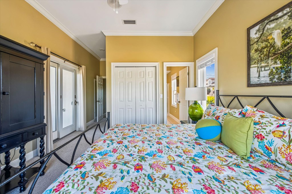 Bedroom with colorful floral bedding, mustard-yellow walls, and a black metal bed frame.