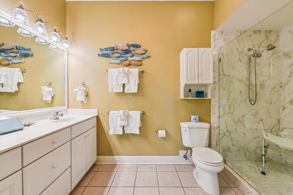 Bathroom with a white double vanity, marble-look tiled shower, and colorful fish wall decor.