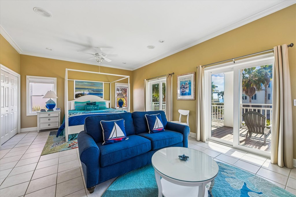 Bedroom suite with a white bed, blue sofa, coastal decor, and sliding doors to a balcony.