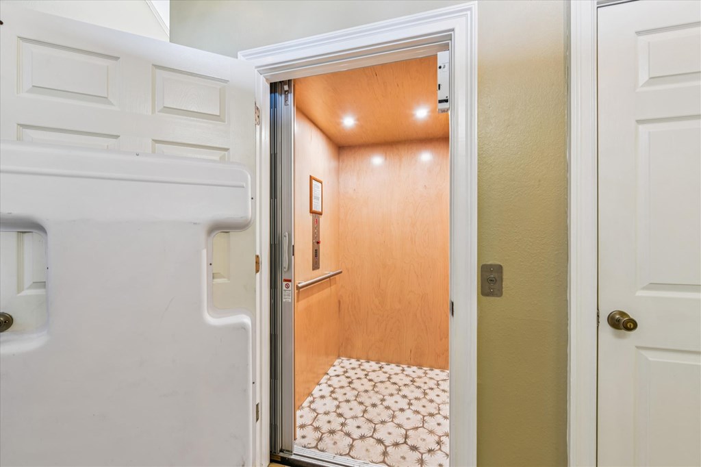 Open residential elevator with wood-paneled walls and a patterned floor.